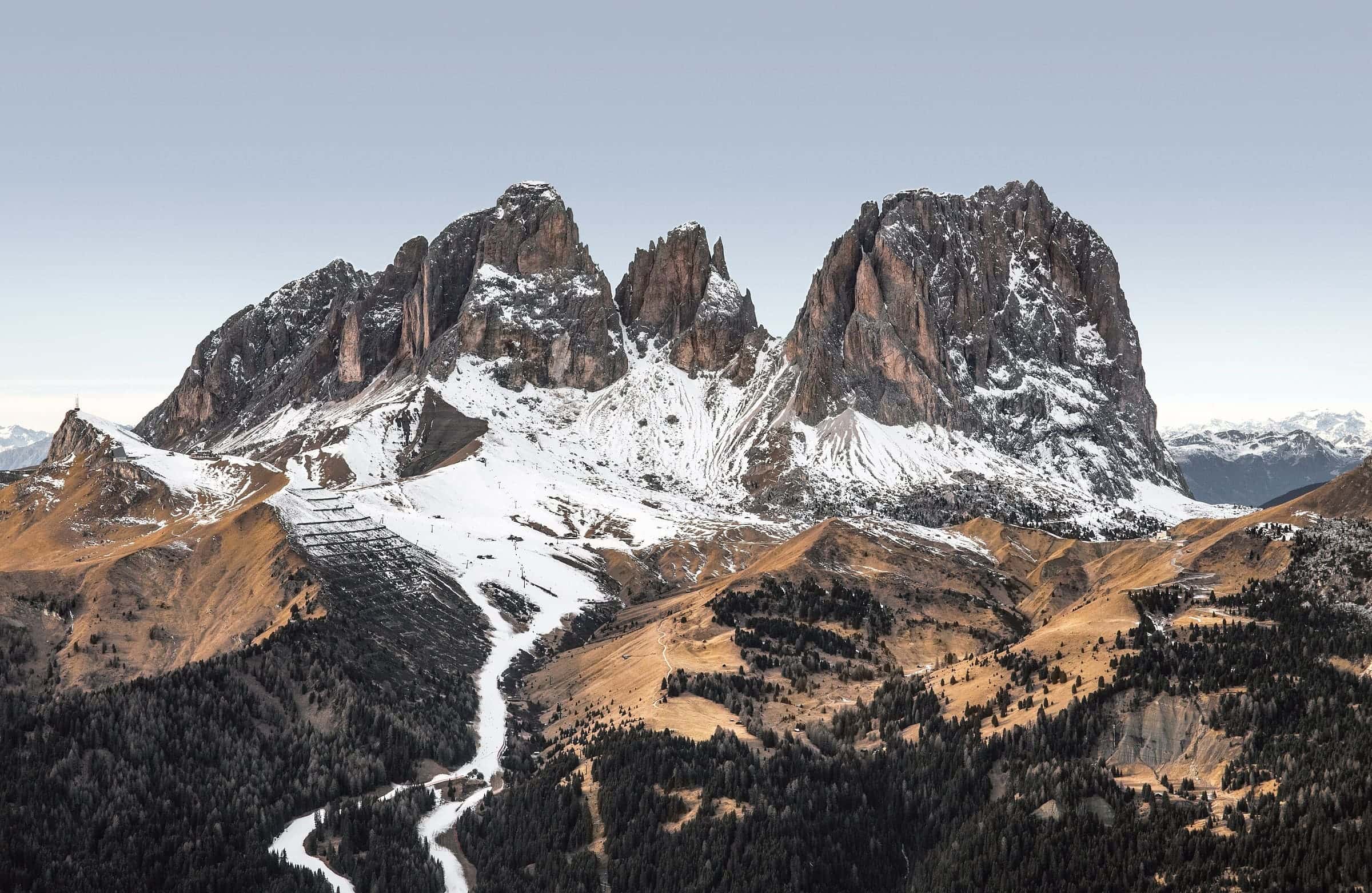 A white line of snow and meltwater winding down from pale Dolomite peaks