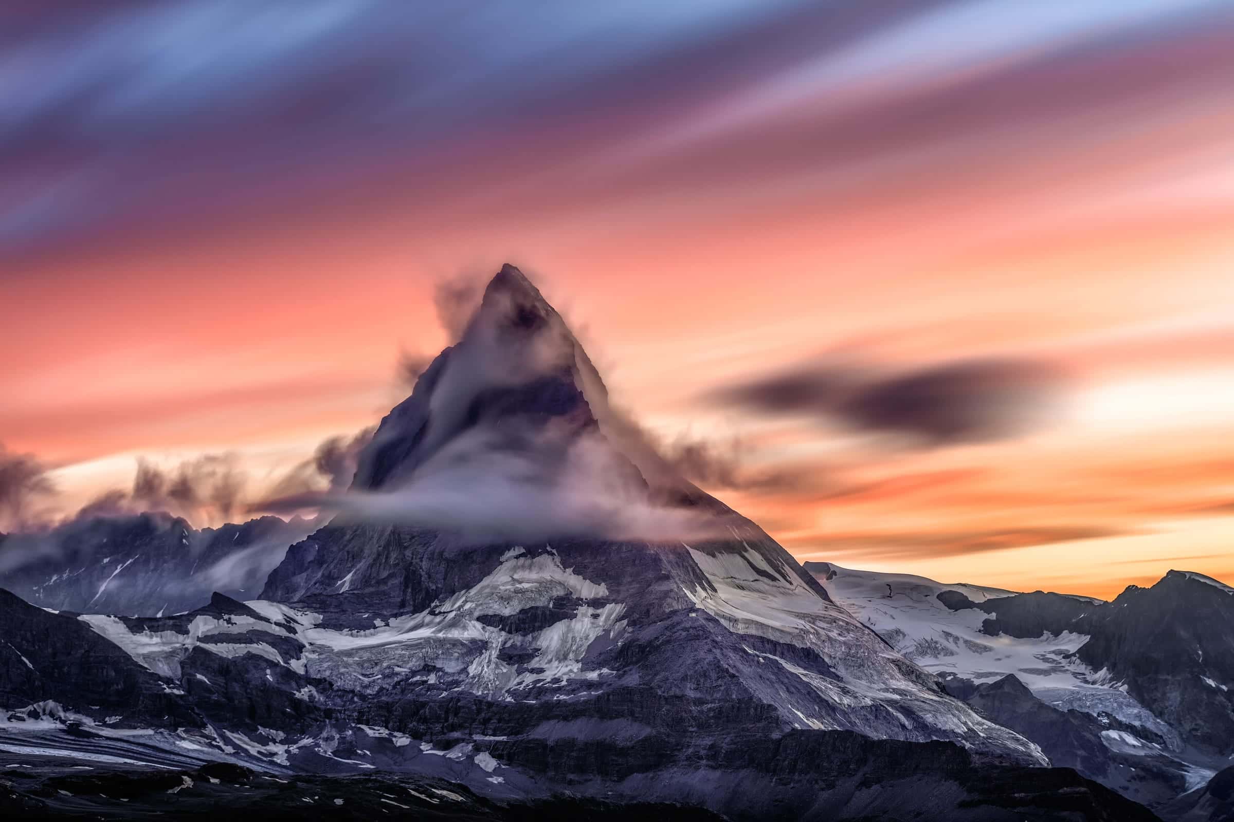 The Matterhorn wrapped in a cloud banner under a streaked pink and orange sky