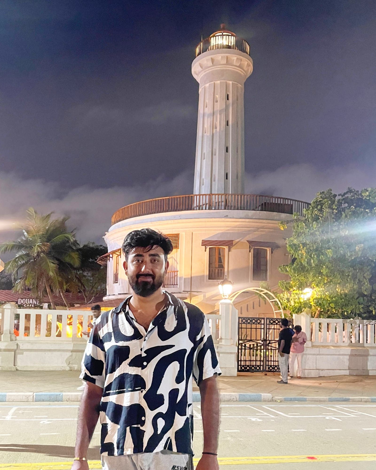 Anurag Gautam in front of a white lighthouse at night