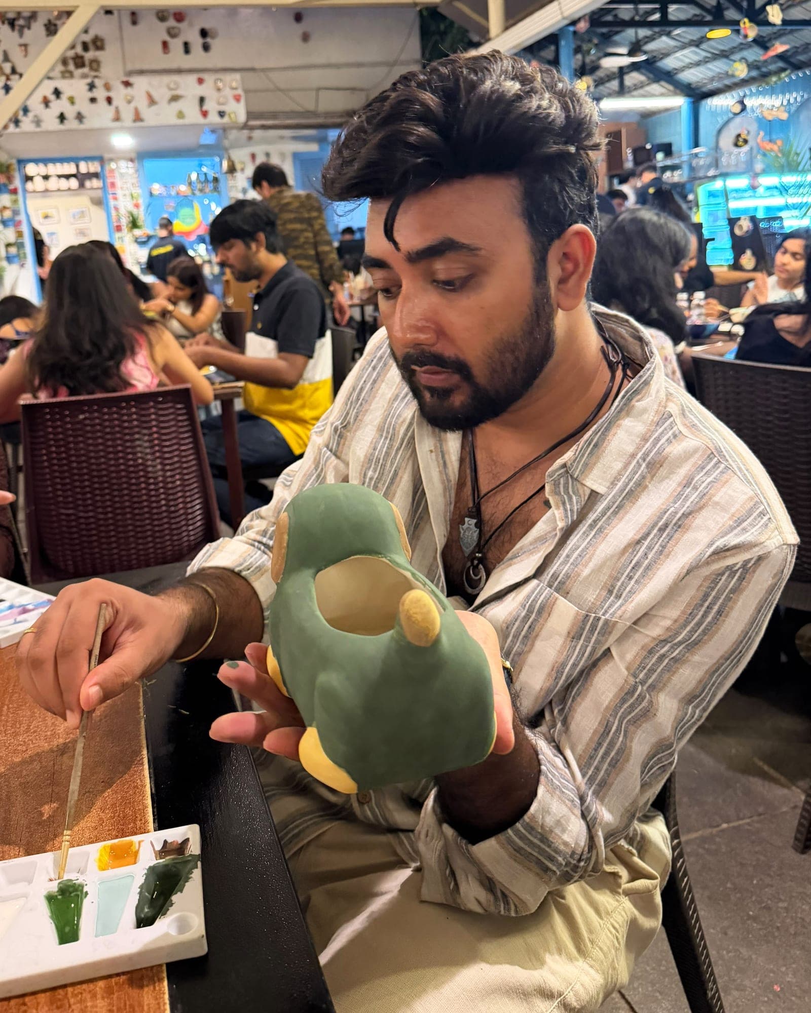 Anurag Gautam painting a pottery dog at a café