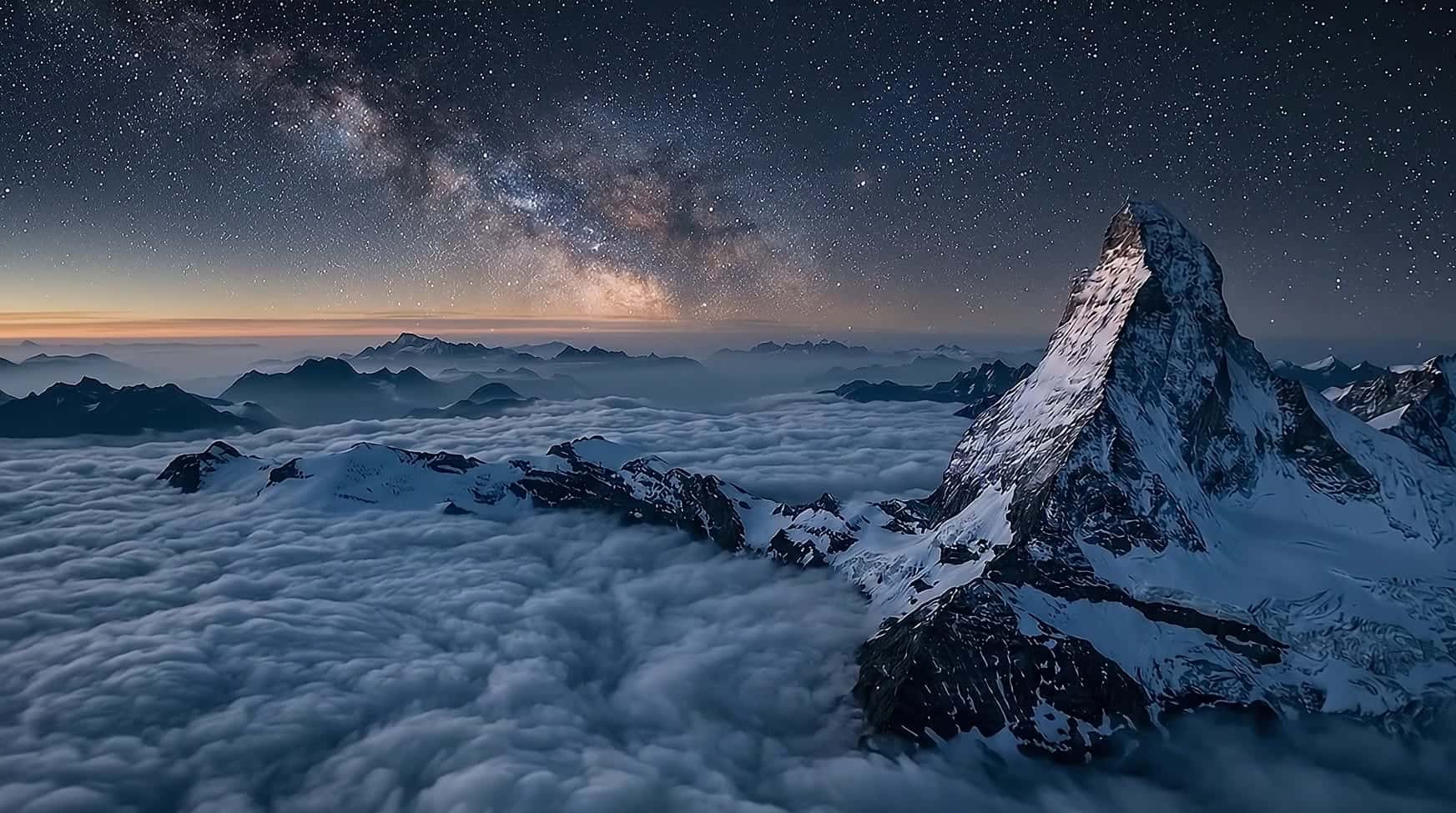 The Matterhorn at night under a full moon and the Milky Way, above a silver sea of cloud